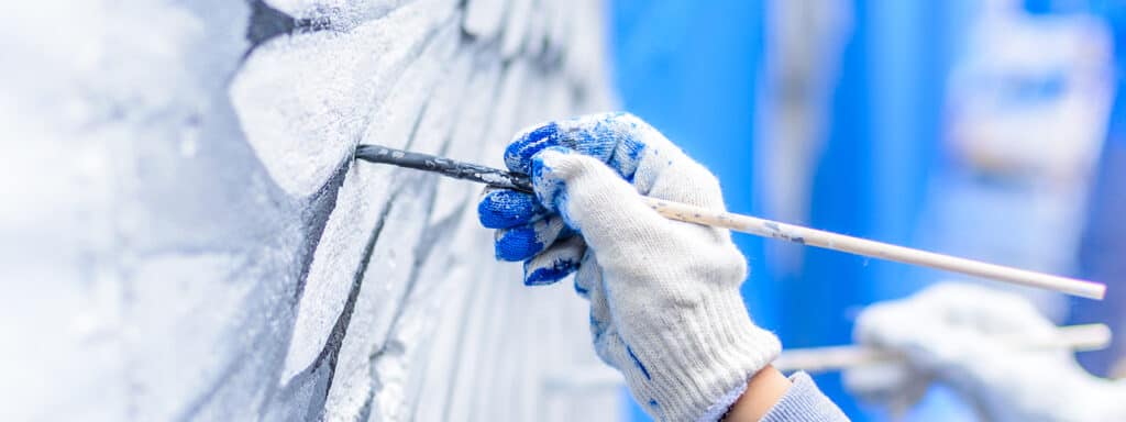 Professionell målare som utför muralmålning på en vägg i ett trapphus